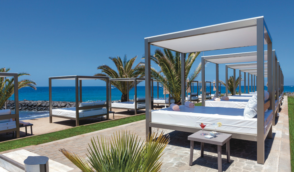 Lettini con baldacchini e palme vicino al mare a Tenerife.