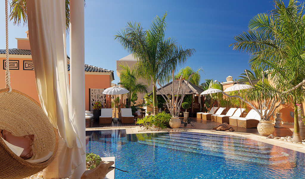 Piscina con lettini e palme in un resort a Tenerife.