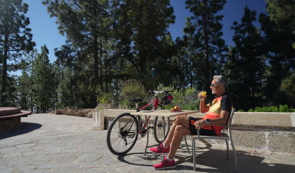 Ciclista seduto a un tavolo, con il suo bicicletta, in un parco a Tenerife.