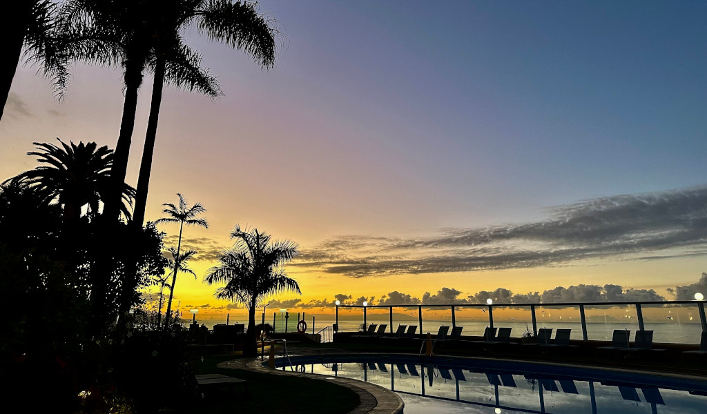 Tramonto su piscina circondata da palme a Tenerife.