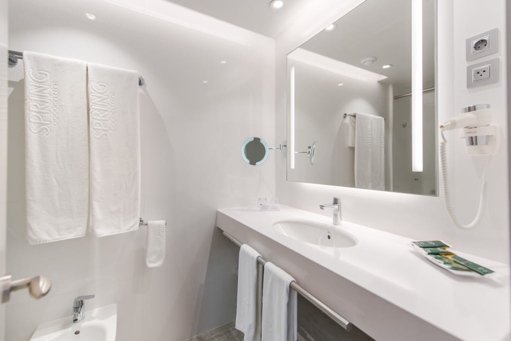 Bagno luminoso con lavabo, specchio illuminato, asciugamani e asciugacapelli a Tenerife.