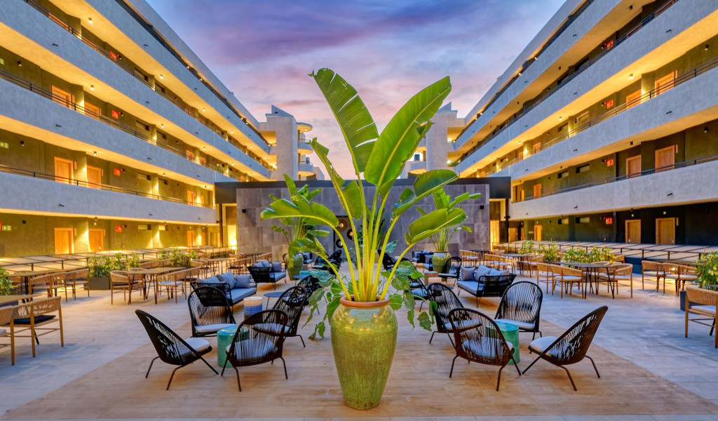 Cortile di un hotel a Tenerife con tavoli, sedie e una pianta centrale.