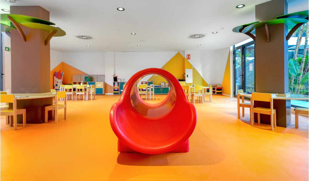Area giochi per bambini con scivolo rosso e tavoli colorati a Tenerife.