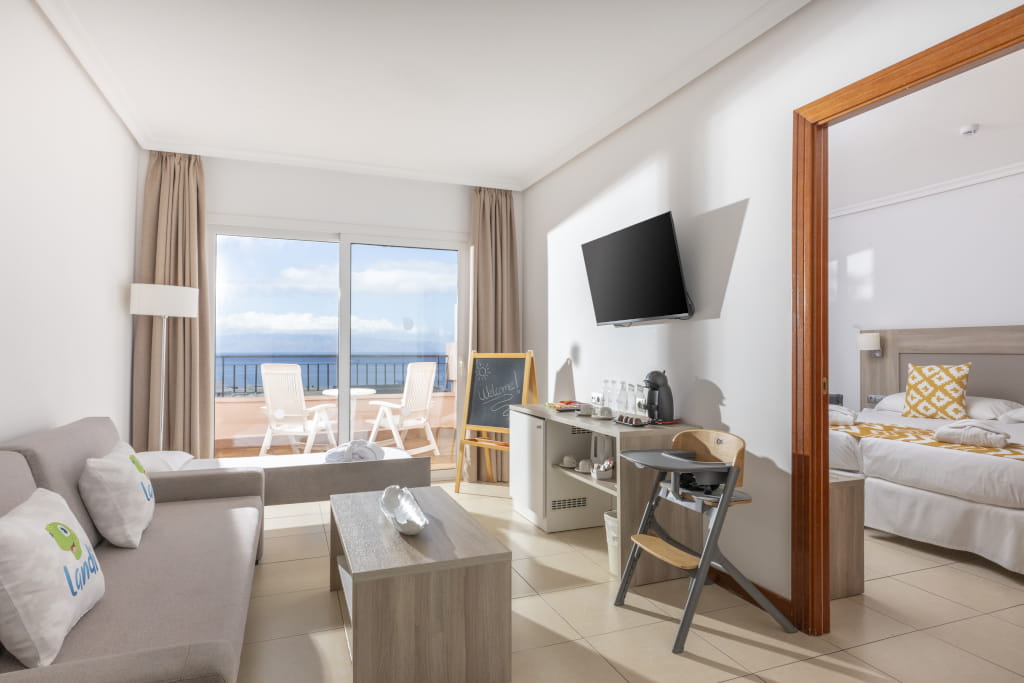 Soggiorno con divano, TV, tavolino e vista sul mare a Tenerife. Scritta Welcome.
