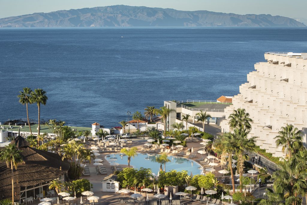 Piscina circondata da palme presso una località turistica a Tenerife con vista sul mare.