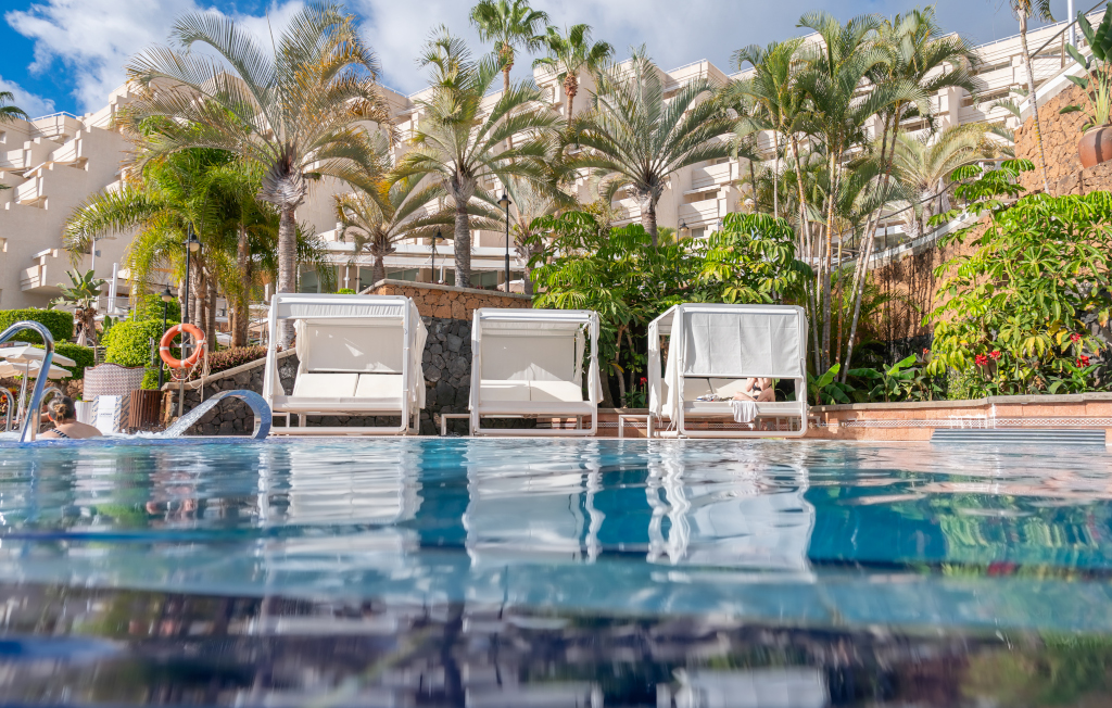 Lettini bianchi vicino a una piscina circondata da palme a Costa Adeje, Tenerife.