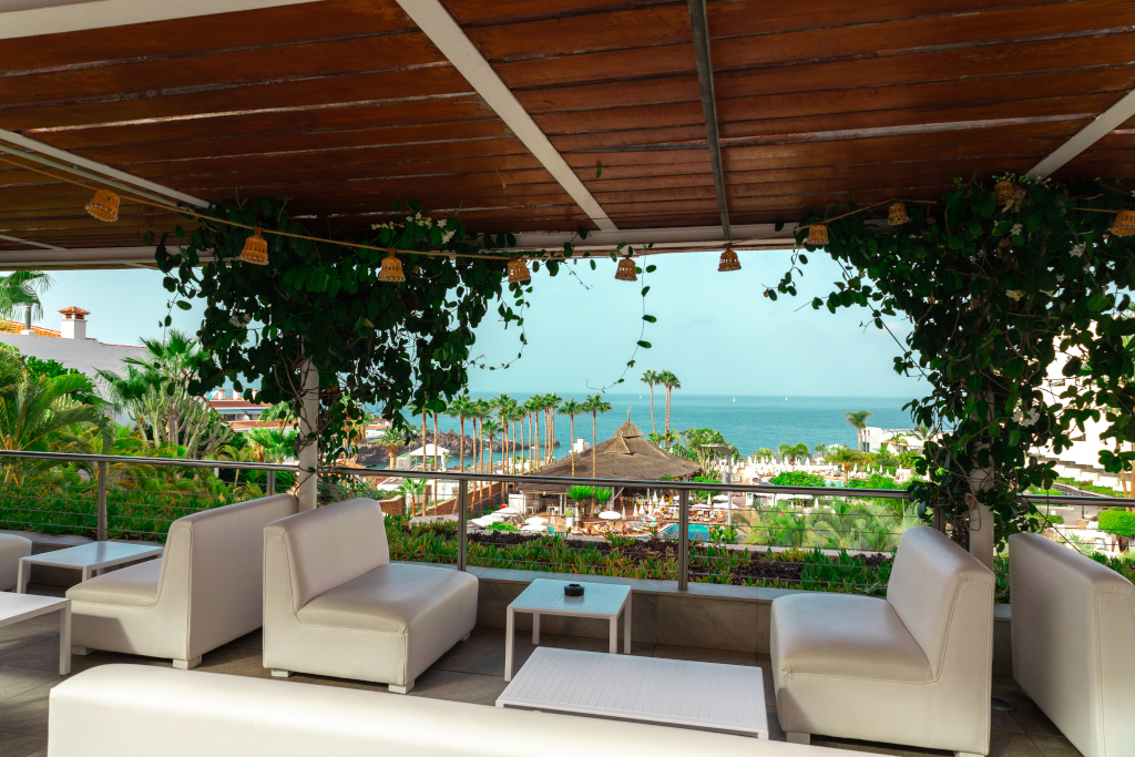 Terrazza con sedie bianche, vista mare e palme a Tenerife.