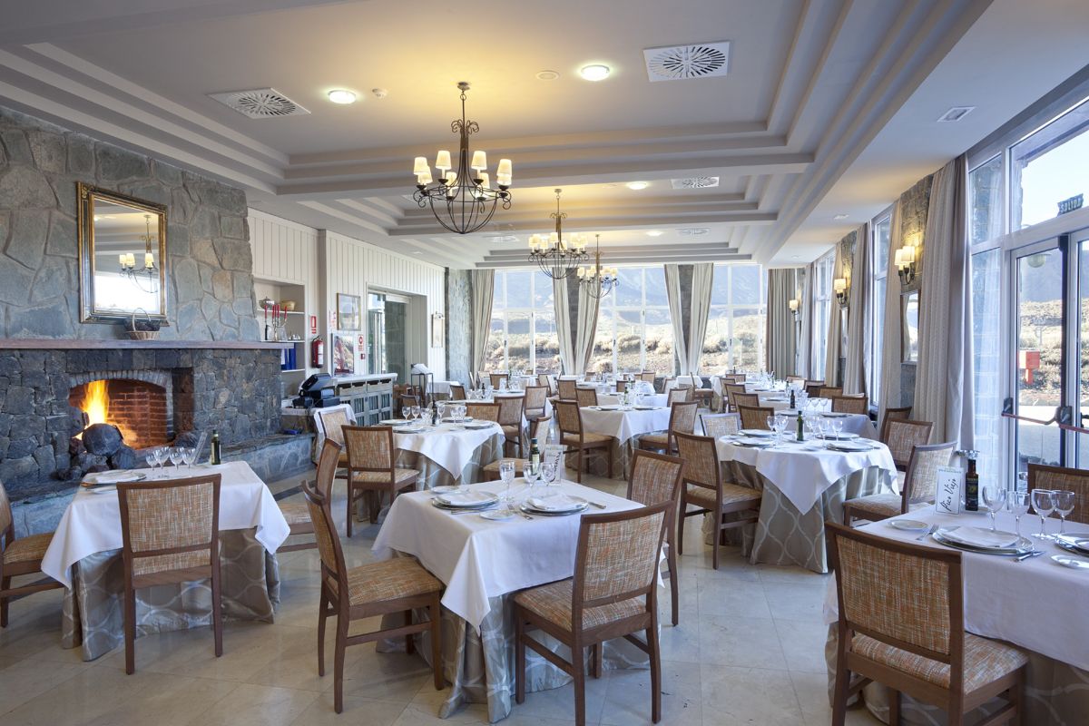 Sala da pranzo elegante con tavoli apparecchiati, camino e vista panoramica a Tenerife.