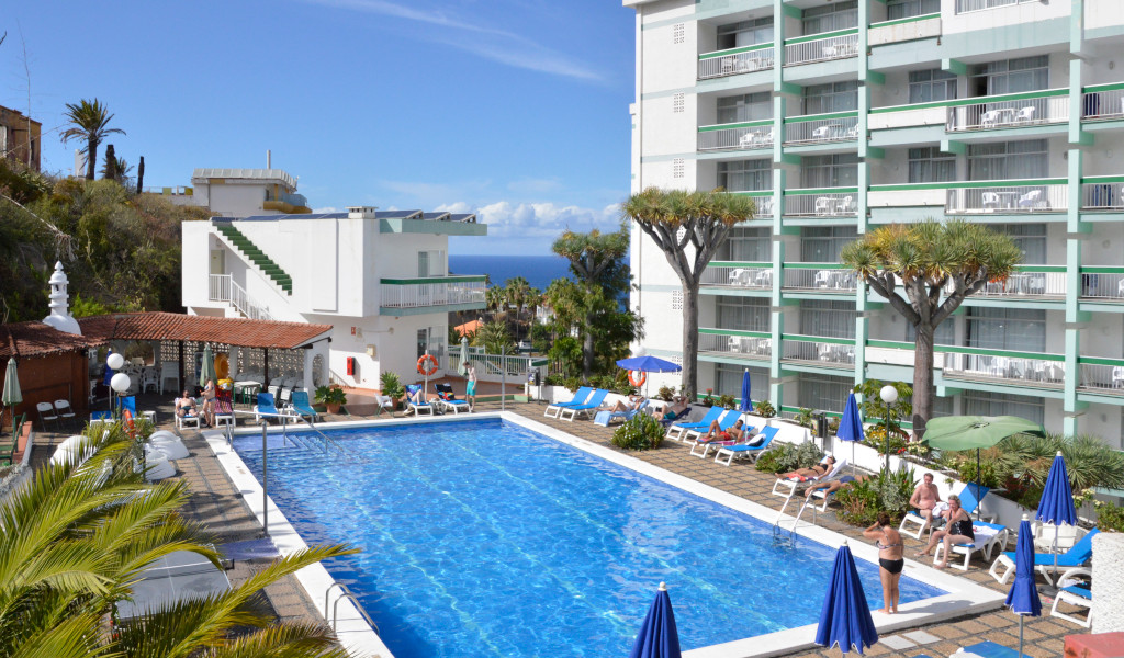 Piscina esterna di un hotel a Puerto de la Cruz, Tenerife, con persone che si rilassano.