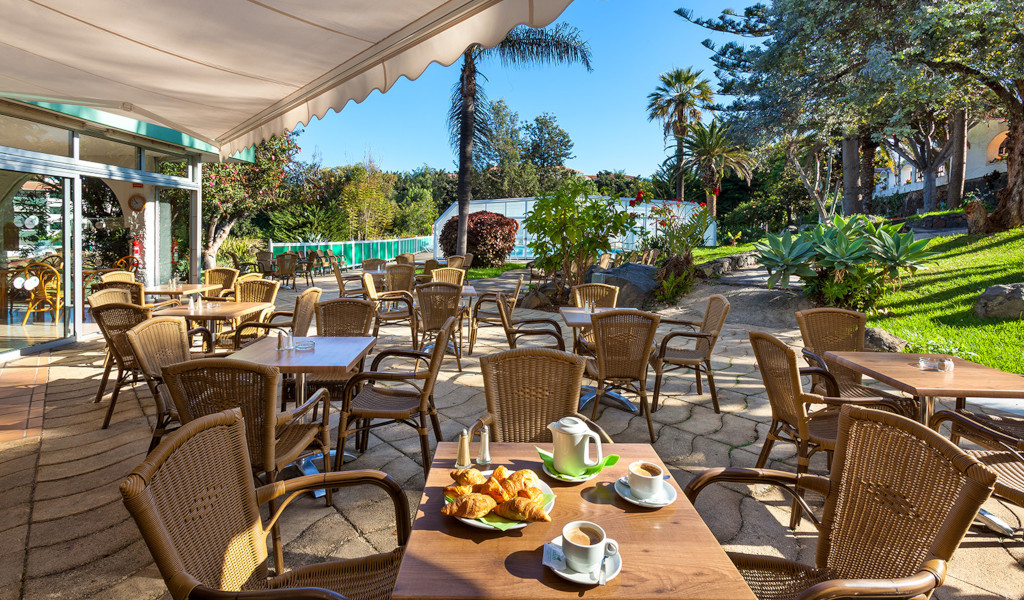 Terrazza di un caffè all'aperto a Puerto de la Cruz con tavoli e sedie di vimini.