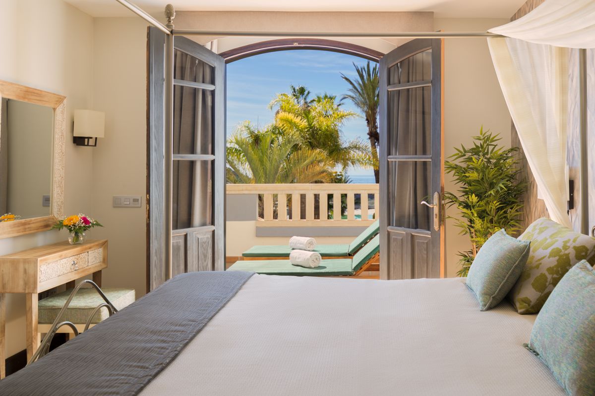 Camera da letto con terrazza e vista su palme a Tenerife.