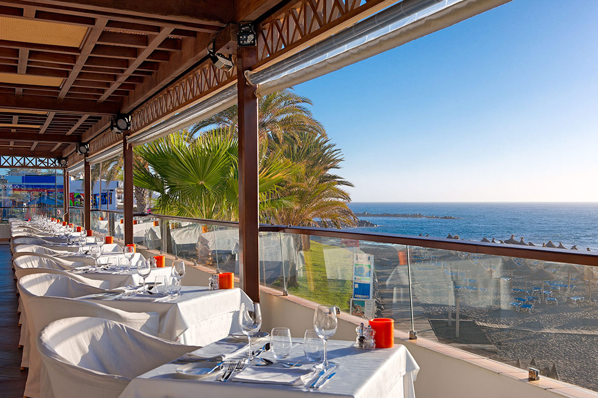 Terrazza di un ristorante a Tenerife con vista mare e tavoli apparecchiati.