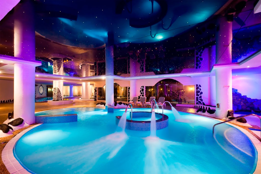 Piscina interna con luci colorate in un centro benessere a Tenerife.