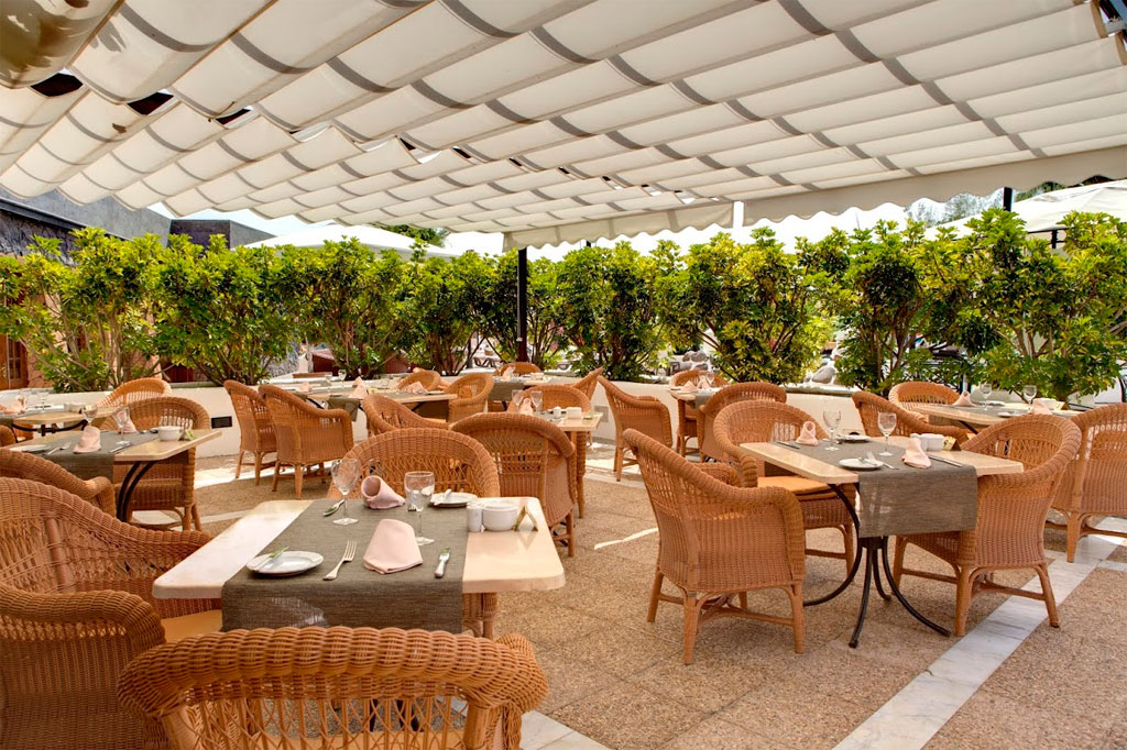 Terrazza ristorante con tavoli e sedie in vimini. Vegetazione sullo sfondo a Tenerife.