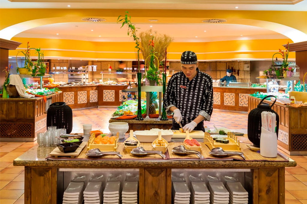 Chef prepara sushi in un ristorante a Tenerife con piatti e utensili sul tavolo.