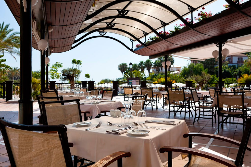Ristorante all'aperto con vista giardino a Tenerife, tavoli apparecchiati sotto tettoia.