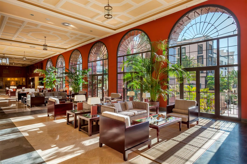 Salone con divani e piante sotto grandi finestre ad arco a Tenerife.