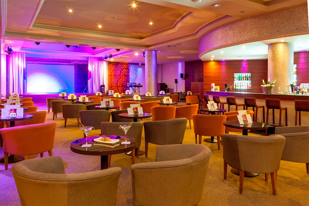 Sala conferenze con sedie e tavolini, bar sullo sfondo a Santa Cruz de Tenerife.