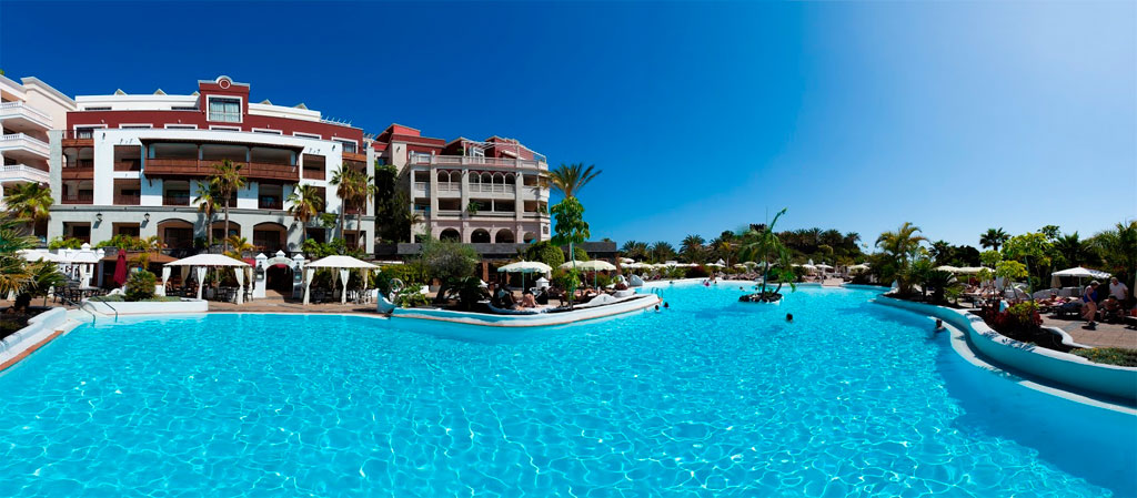 Piscina all'aperto in un hotel a Tenerife con palme e ombrelloni.