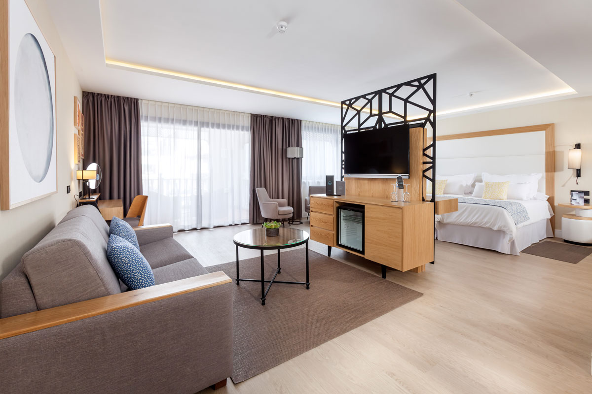Suite moderna hotel con divano, tavolo, letto e televisore a Tenerife.