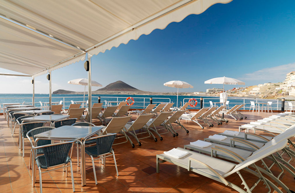 Sedie a sdraio e tavoli su una terrazza con vista mare a El Médano, Tenerife.