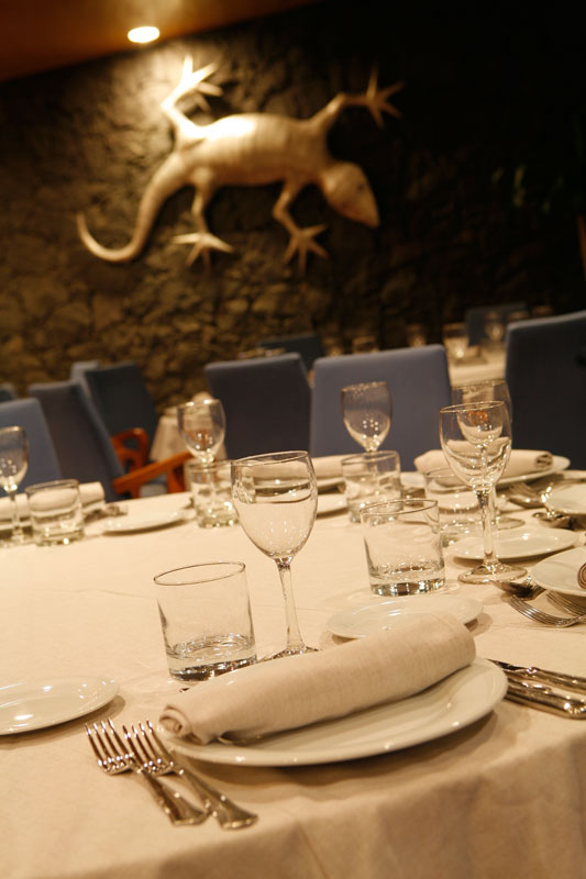 Tavolo apparecchiato in un ristorante a Tenerife con lucertola decorativa sulla parete.