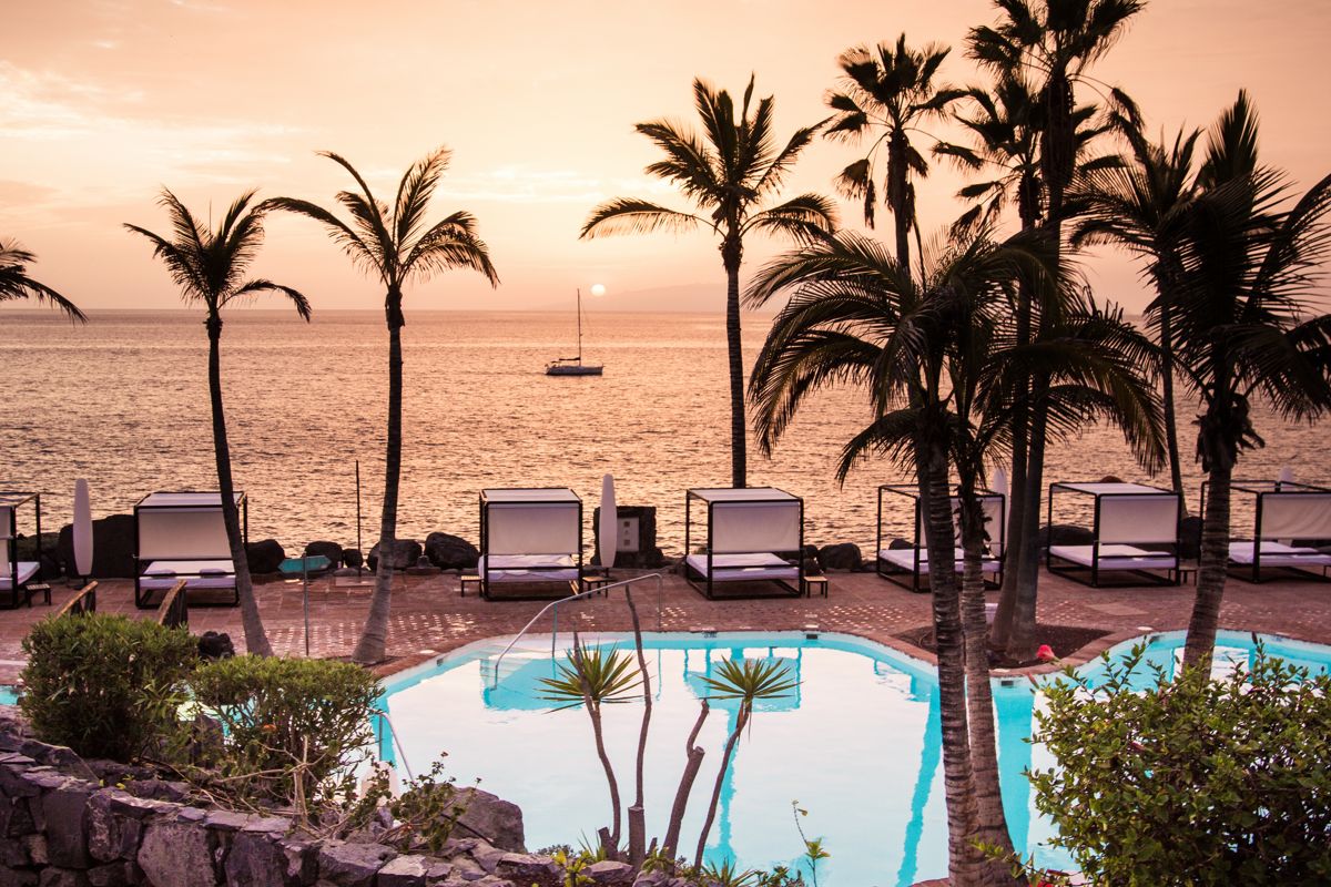 Piscina con palme al tramonto a Tenerife, vista sul mare.