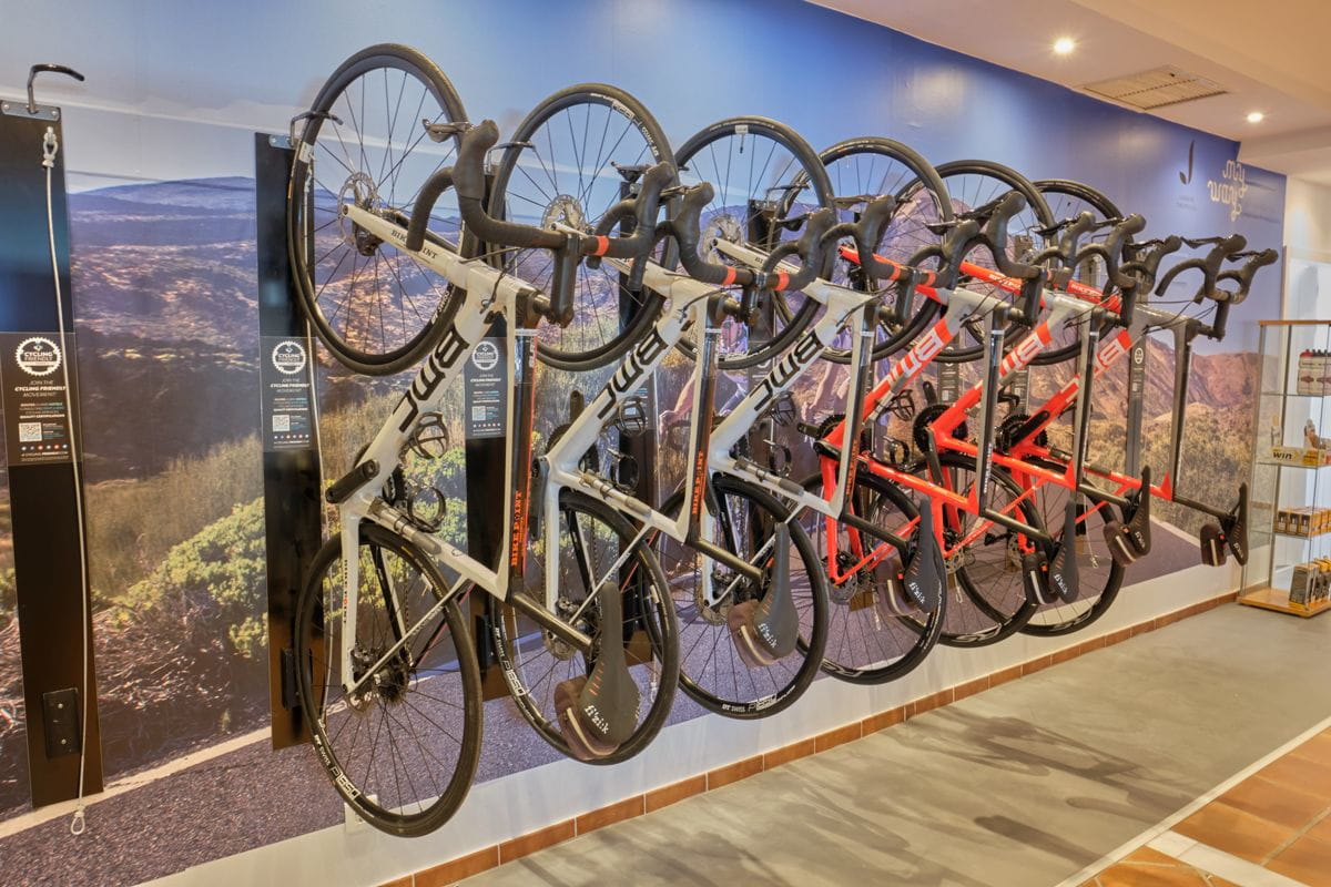 Biciclette appese al muro in un negozio a Tenerife con sfondo di montagna.