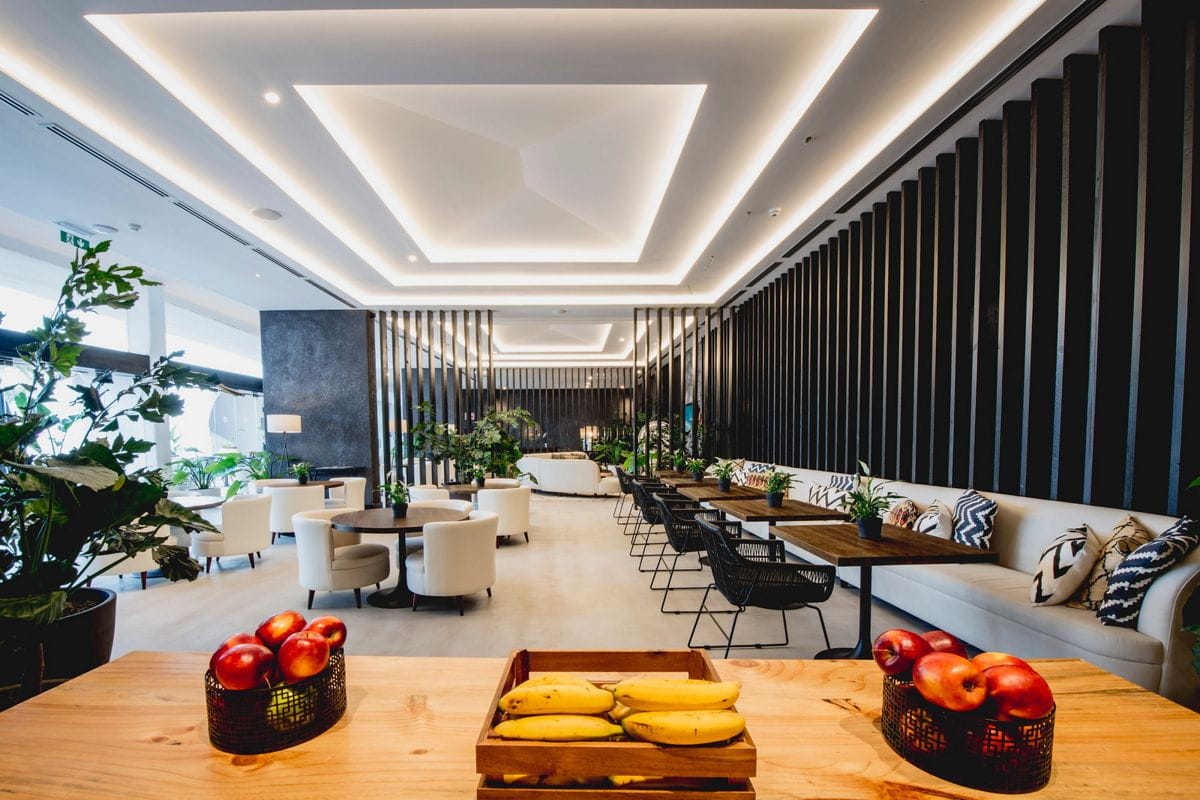 Sala moderna con tavoli, sedie bianche, piante e frutta su un tavolo a Tenerife.