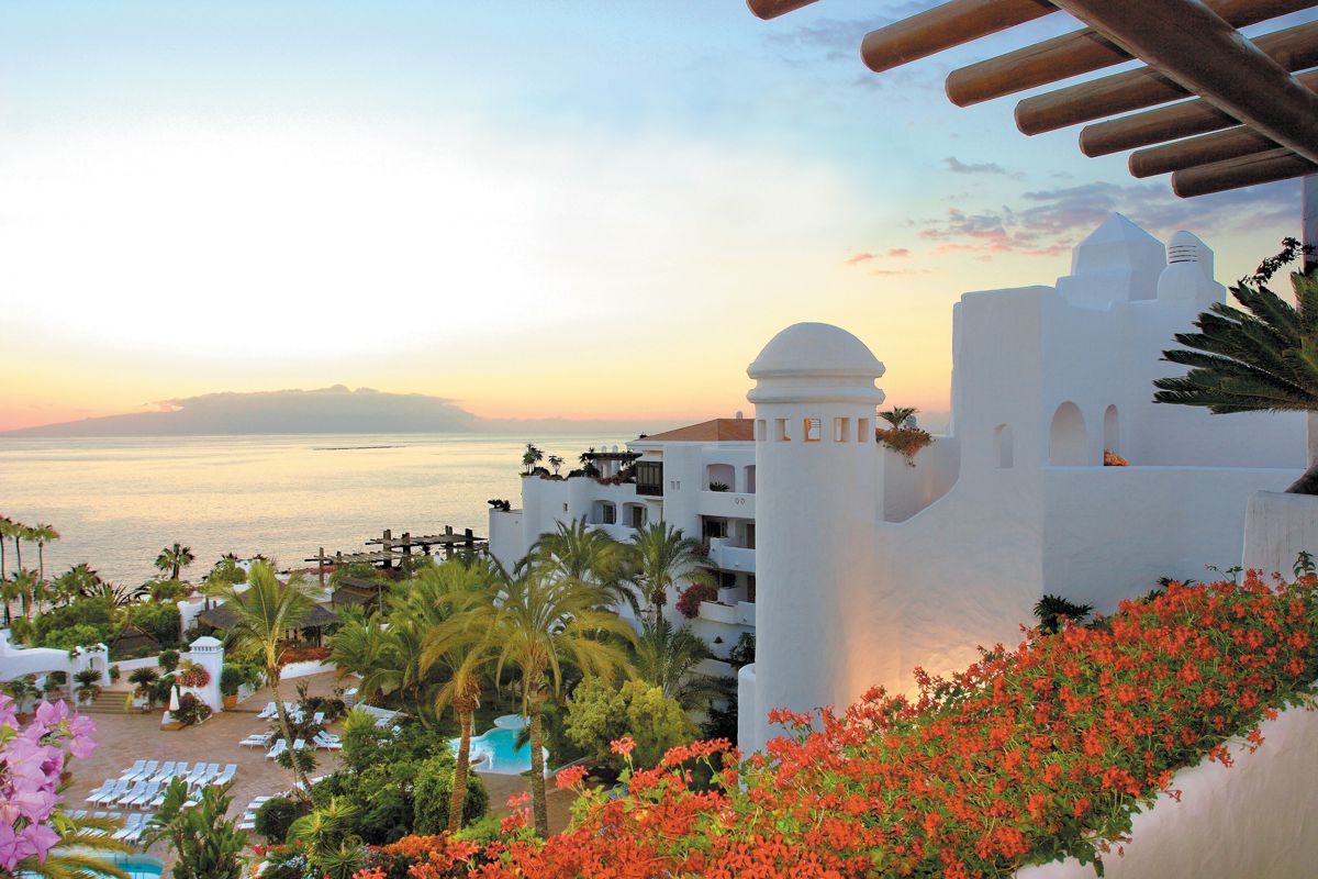 Edificio bianco con piscina e vista mare al tramonto a Tenerife.