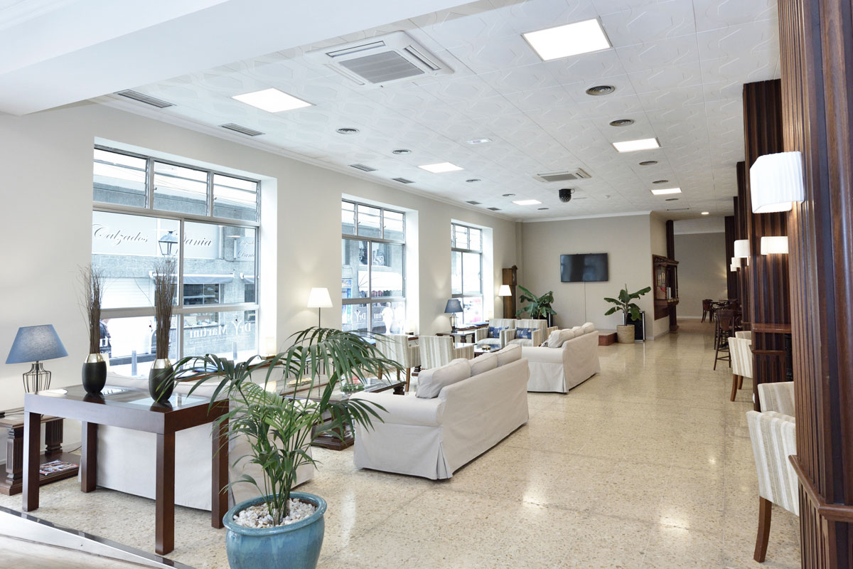 Sala d'attesa luminosa con divani e piante, vista strada a Tenerife.