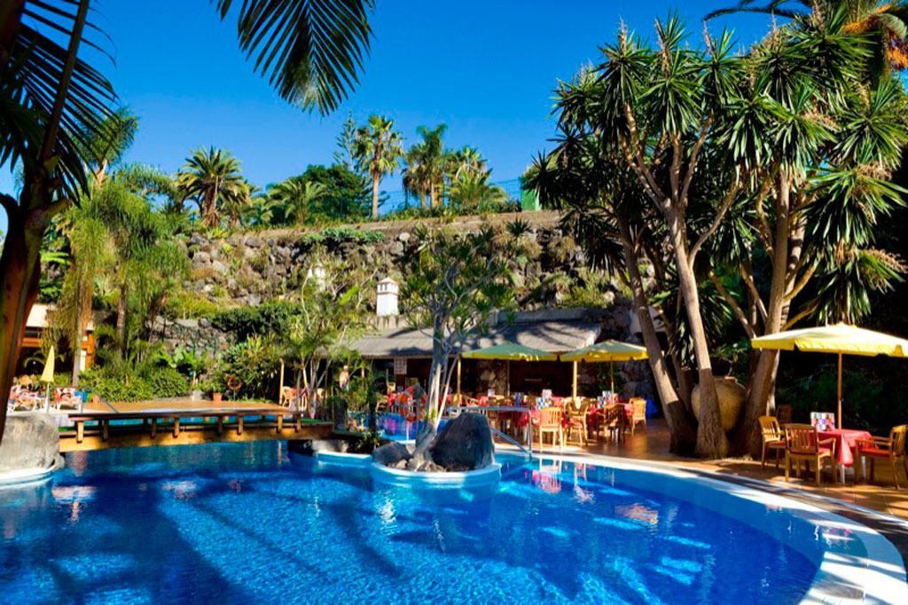 Piscina circondata da palme e tavoli all'aperto a Tenerife.