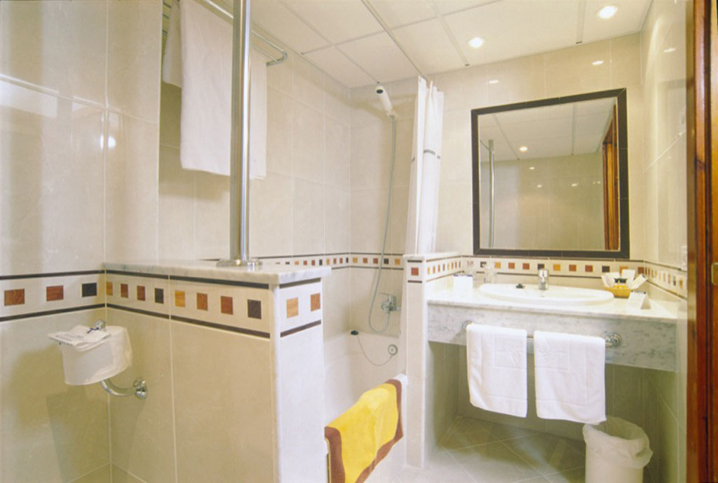 Bagno con doccia, lavandino e specchio in un hotel a Tenerife.
