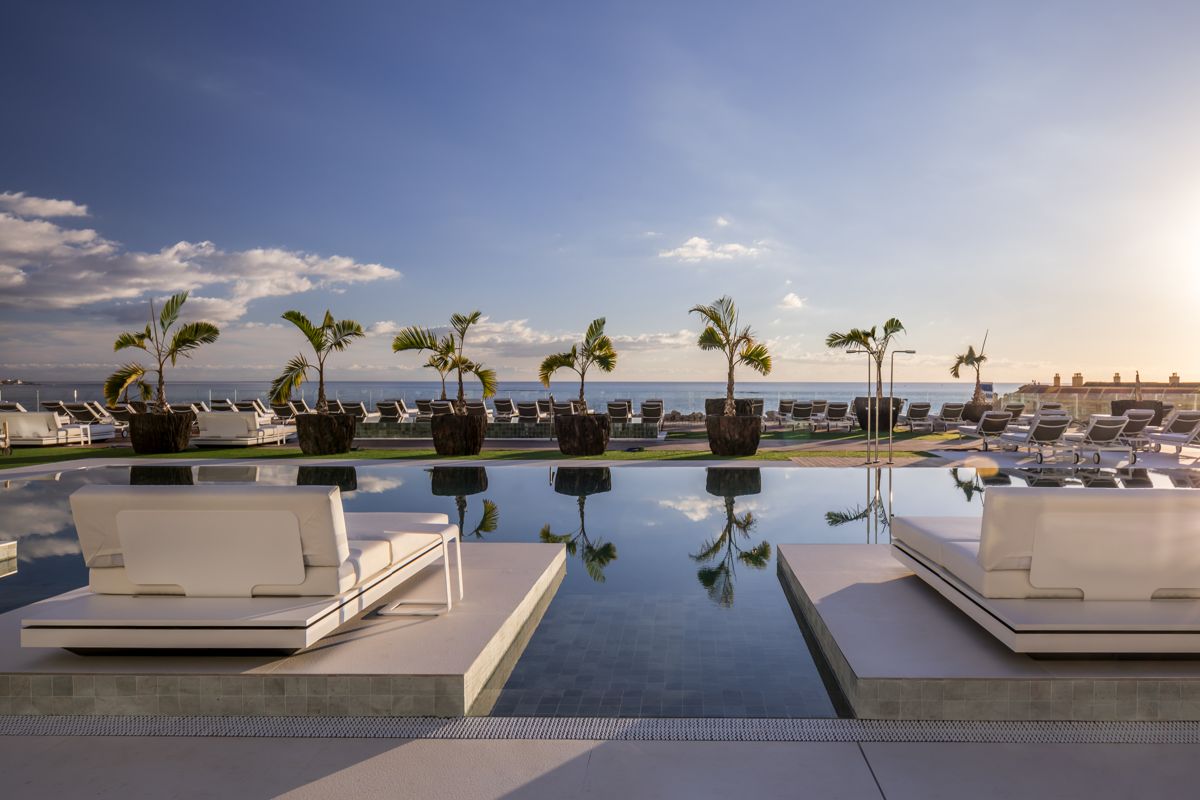 Sedie a sdraio e palme vicino a piscina con vista mare a Tenerife.
