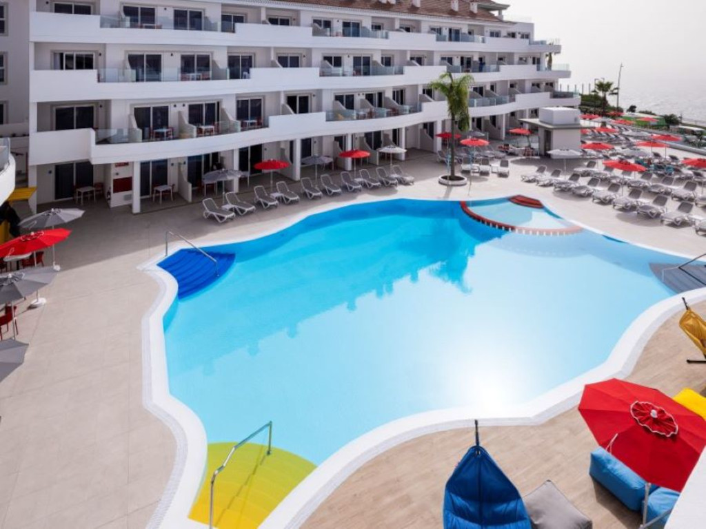 Piscina circondata da sdraio e parasoli in un complesso turistico a Tenerife.