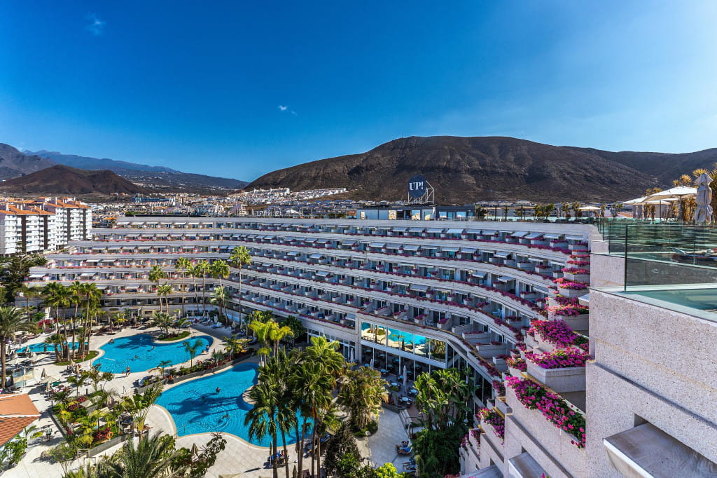 Edificio e piscine del complesso UP! Tenerife con montagne sullo sfondo.