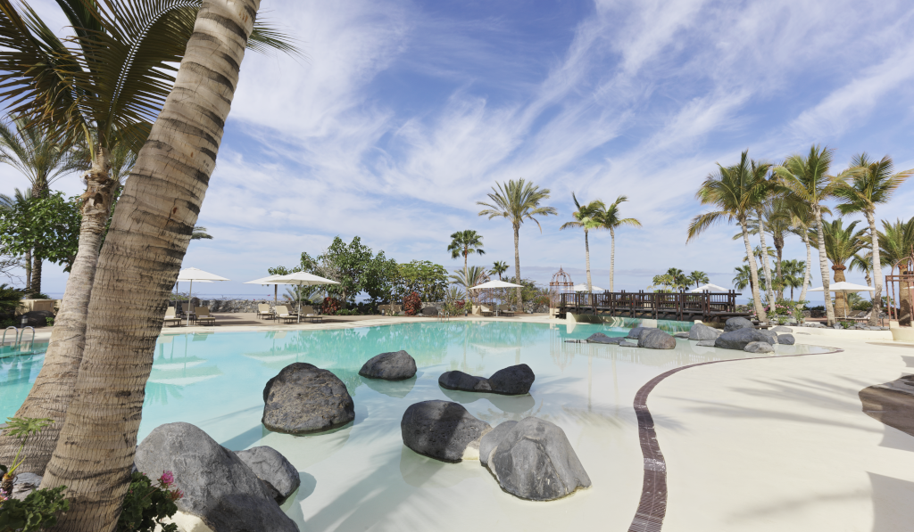 Piscina all’aperto con palme e rocce a Costa Adeje, Tenerife.