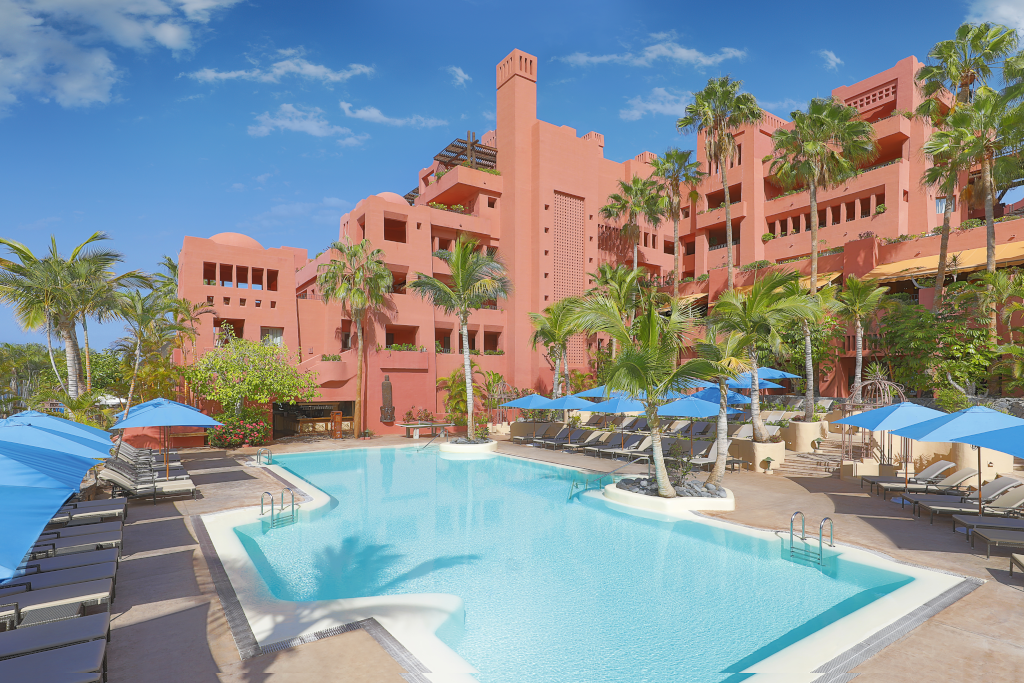 Piscina e hotel rosso circondati da palme a Tenerife.
