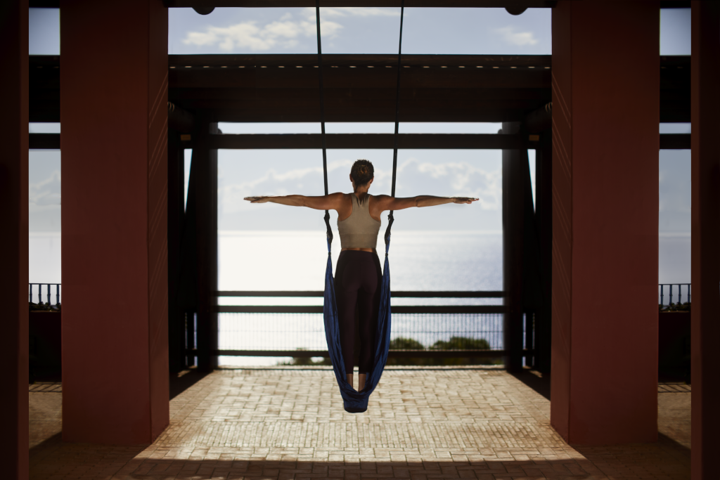 Persona che pratica lo yoga sospeso con vista sull'oceano a Tenerife.