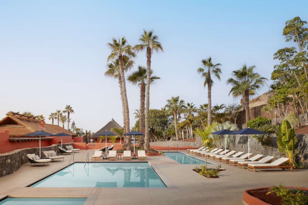 Piscina con lettini e palme in un resort a Tenerife.