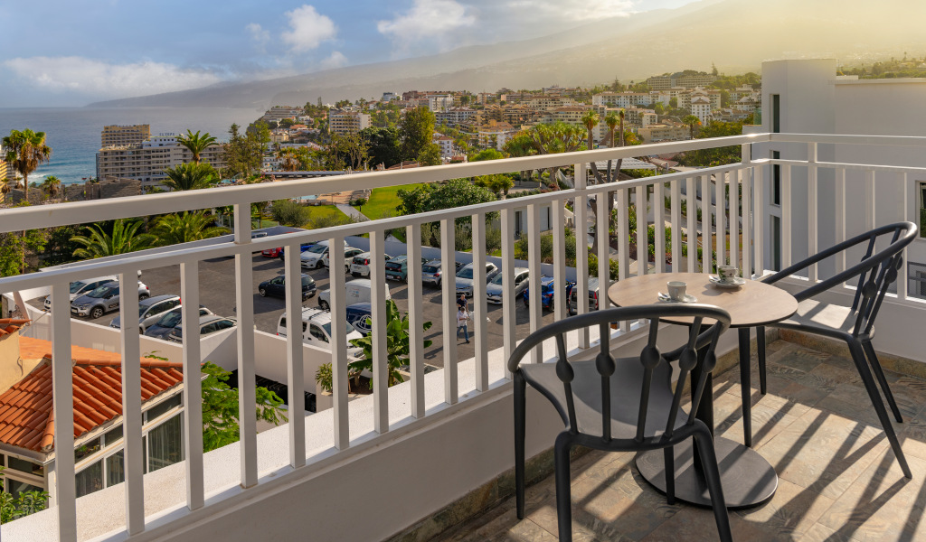 Vista dal balcone su Puerto de la Cruz, Tenerife, con città e oceano sullo sfondo.