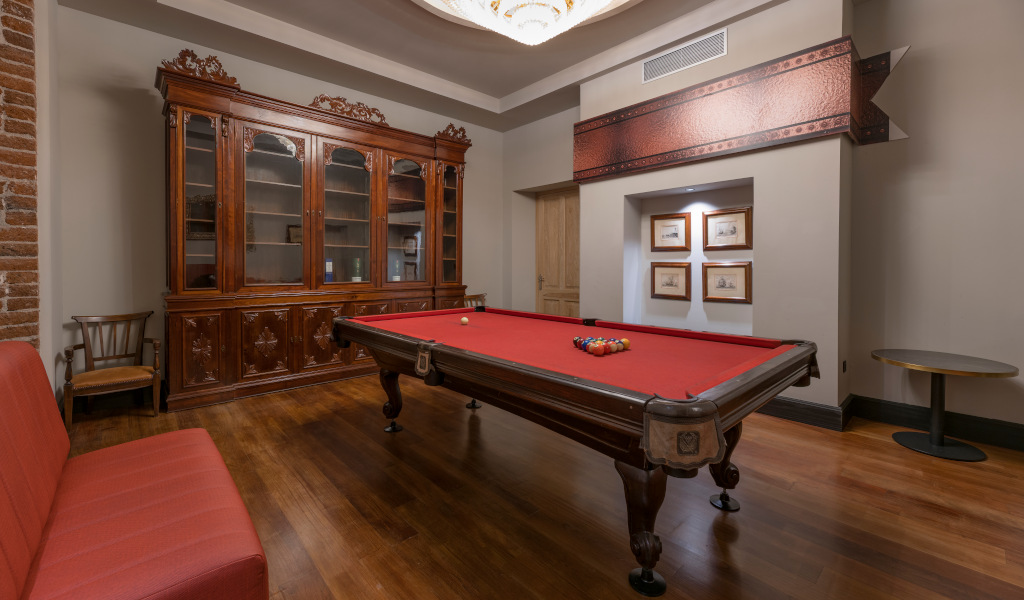 Sala da biliardo con tavolo rosso, mobili antichi e quadri; luogo a Tenerife.