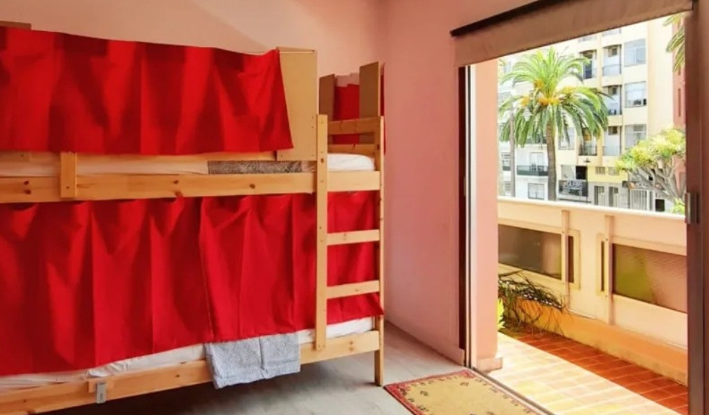 Letto a castello con tende rosse, finestra aperta su Santa Cruz de Tenerife.