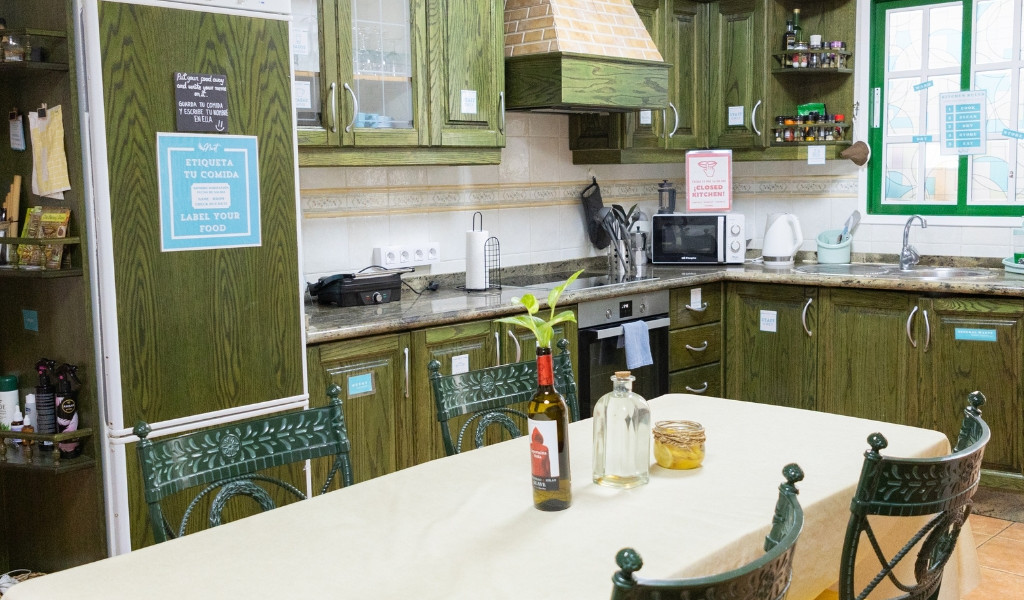 Cucina in legno con tavolo apparecchiato, cartello ETIQUETA TU COMIDA.