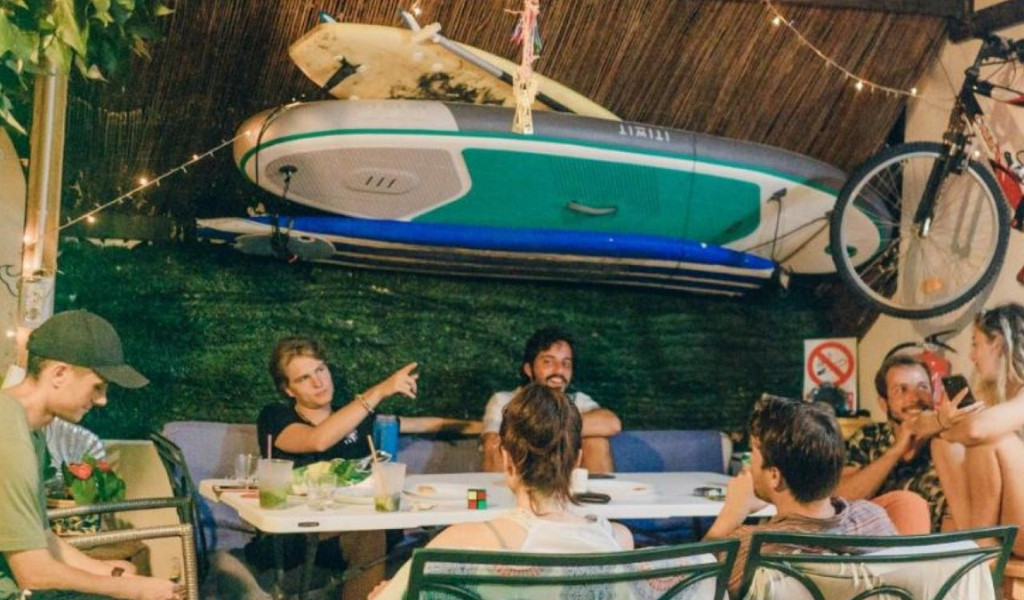 Persone conversano in un patio con un paddleboard e una bici appesi a Tenerife.