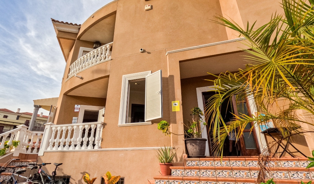 Edificio beige con balcone e piante a Puerto de la Cruz, Tenerife.
