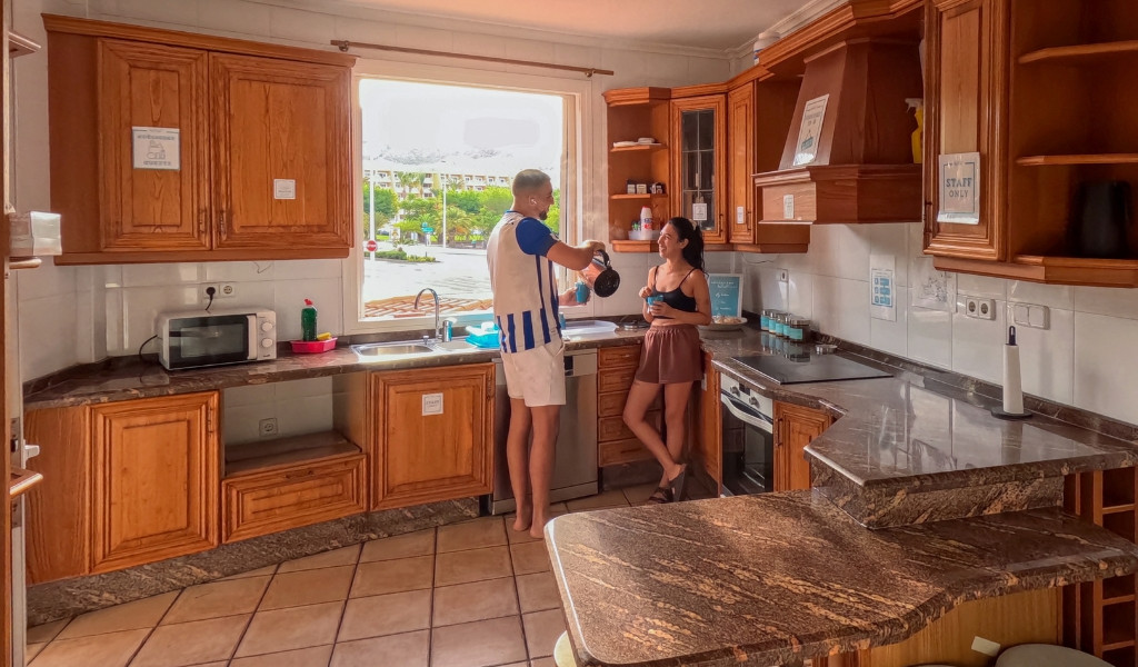 Due persone in una cucina di Tenerife preparano il caffè vicino a una finestra.