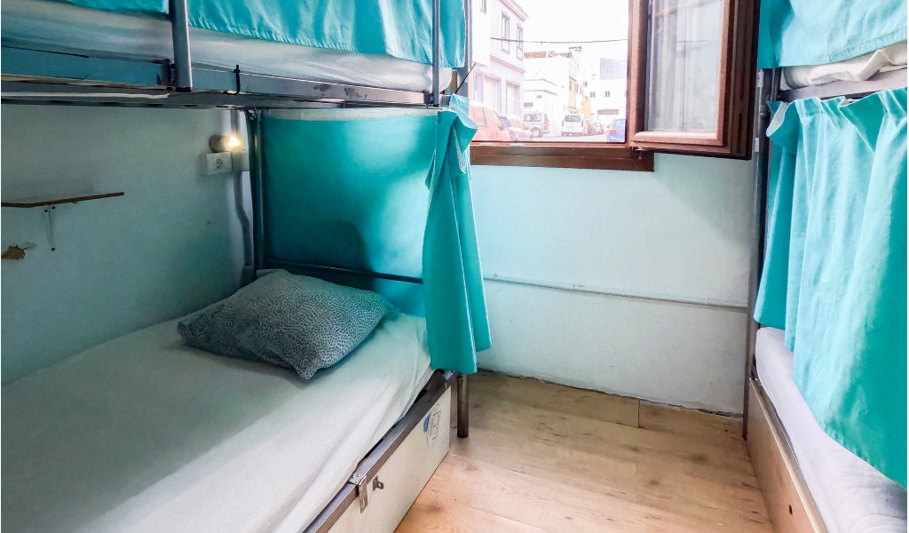 Letto a castello con tende azzurre, finestra aperta con vista su strada a Tenerife.
