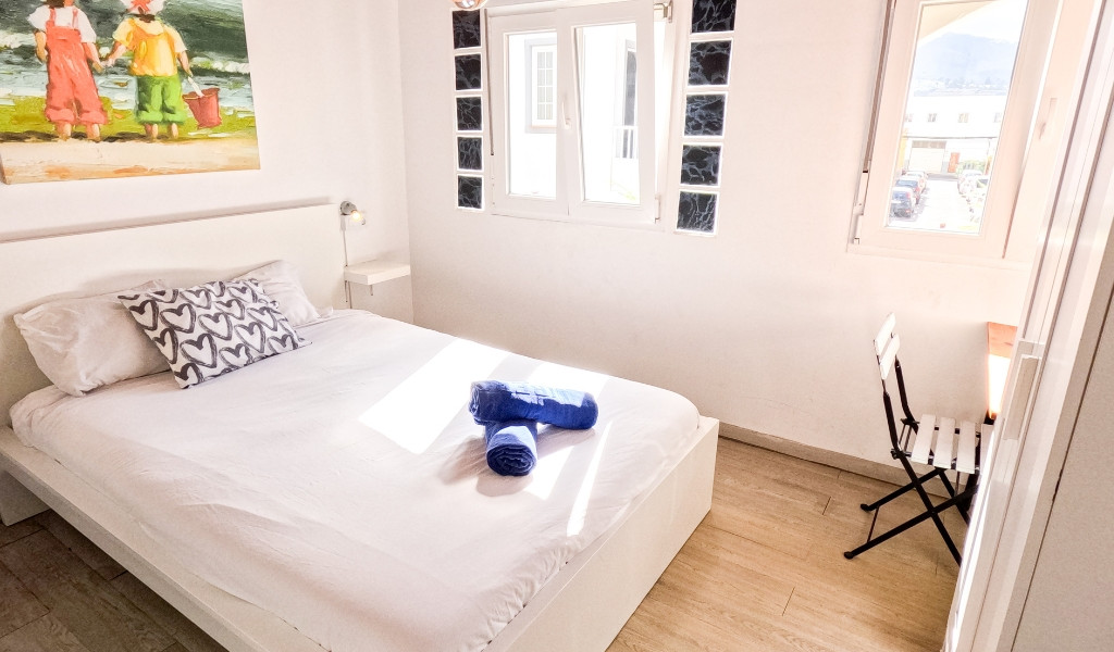 Camera da letto luminosa a Santa Cruz de Tenerife con letto, finestra e sedia.