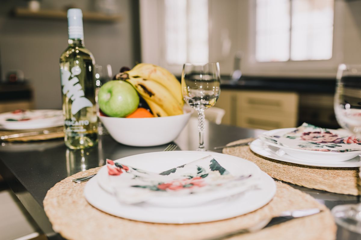 Tavola apparecchiata con piatti, bicchiere, bottiglia di vino e frutta a Tenerife.